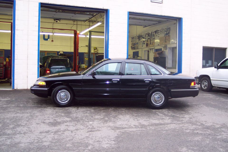 Black 2001 Ford Crown Victoria sedan parked outside a garage