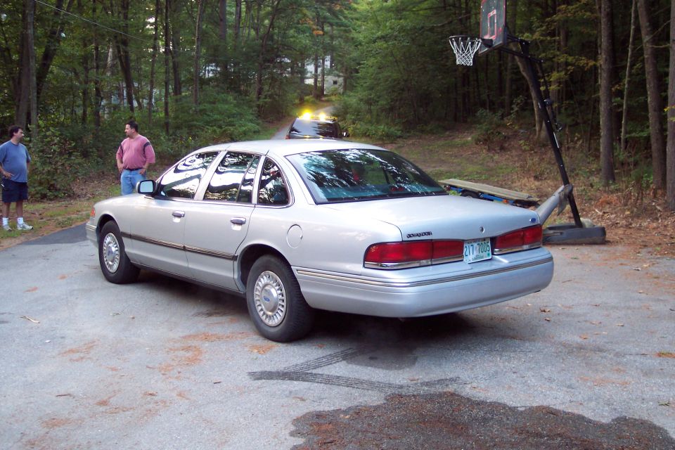 2001 Ford Crown Victoria parked on a driveway with two men standing nearby and another car in the distance