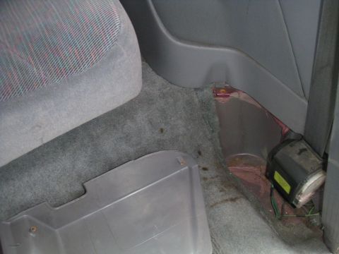 1994 Ford Bronco - Interior view of a vehicle's passenger side, focusing on the floor and seat base with visible carpet and seatbelt components.
