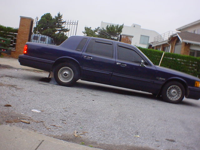 dark blue sedan parked on asphalt, rear tire is flat