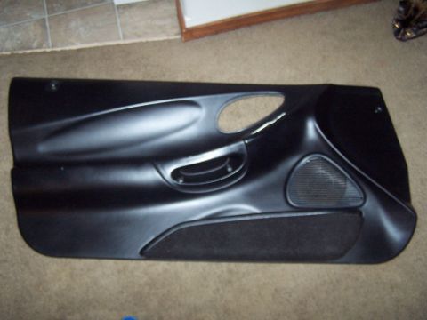 1994 Ford Probe - A black car door panel with a speaker grille and fabric insert is shown laid flat on the floor.