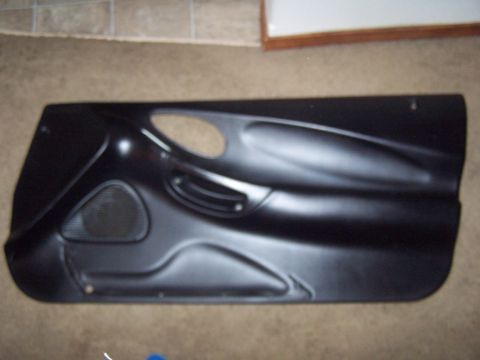 1994 Ford Probe - A black car door panel, likely for a coupe, is shown lying flat on a carpeted surface.