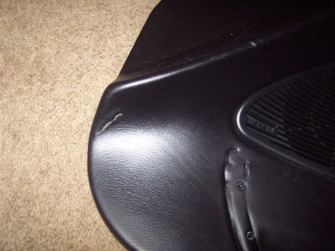 1994 Ford Probe - Close-up of a car's interior door panel, showing a speaker grille and some damage.