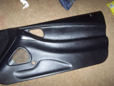 1994 Ford Probe - Car door panel with speaker grille opening and handle recess shown on carpet.