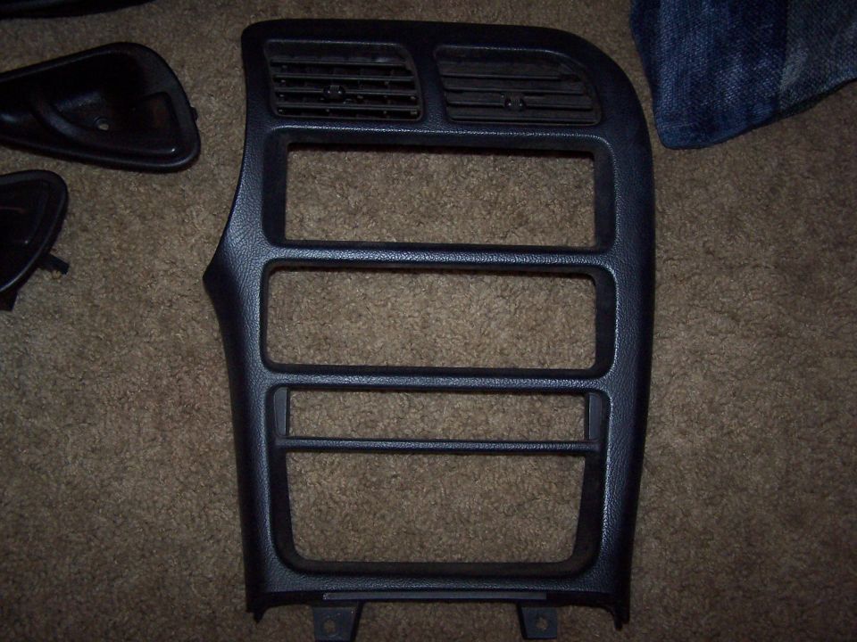 Black plastic dashboard trim panel with three rectangular openings and two horizontal air vents