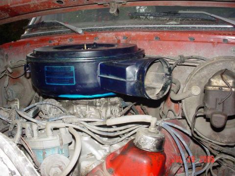 1979 Ford F-150 - Dusty engine bay of a red vehicle showing a blue round Motorcraft air cleaner housing with a long snorkel inlet tube sitting atop a carbure…