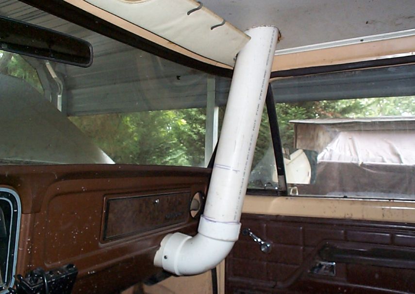 Homemade white PVC snorkel tube running up the A-pillar seen from inside a brown truck cab