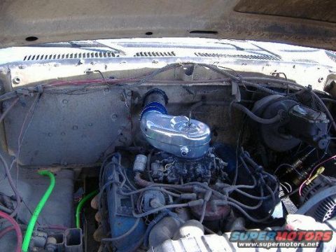 1979 Ford F-150 - Under-hood view of a dusty white truck's engine bay with a chrome oval air cleaner and blue snorkel adapter sitting on the carburetor of a…