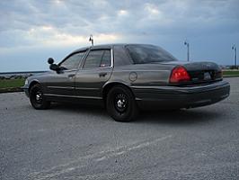 2000 Ford Crown Victoria - A dark 2000 Ford Crown Victoria is seen from a 3/4 front angle, parked outdoors under a cloudy sky.