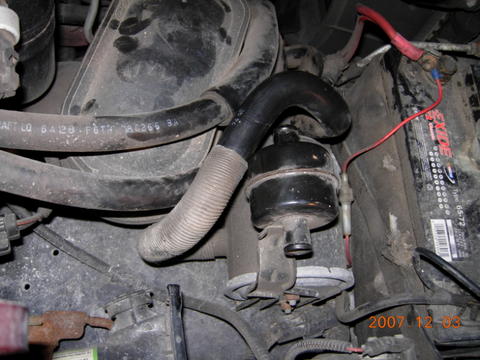1996 Ford Bronco - Close-up view of engine bay components including a battery and various hoses.