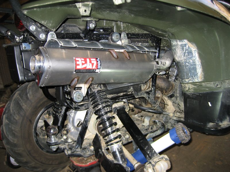 Yoshimura exhaust muffler installed on green ATV, showing suspension and swingarm