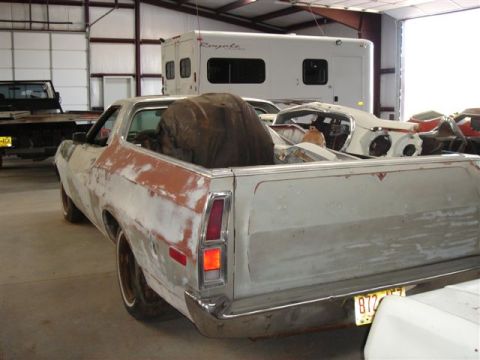 1972 Ford Ranchero - This 1972 Ford Ranchero shows primer and rust, with a large, dark object in its bed, parked indoors.