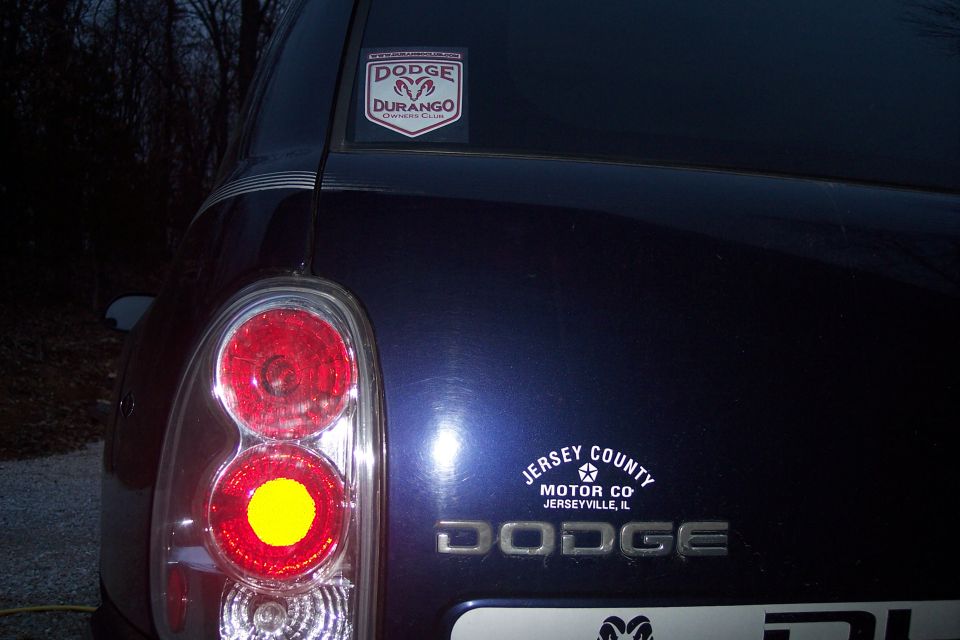 Rear liftgate of a dark blue Dodge Durango with clear taillight and Owners Club sticker