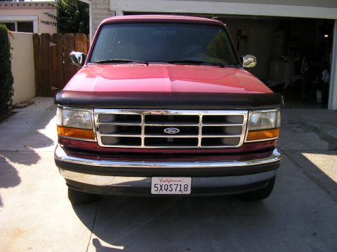 1994 Ford Bronco - Front view of a red Ford truck with a chrome grille and a bug deflector.
