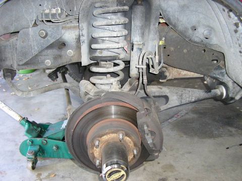 1994 Ford Bronco - Close-up view of the front suspension and brake assembly, including the coil spring, shock absorber, and brake rotor.