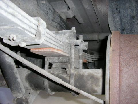 1994 Ford Bronco - Close-up view of a vehicle's rear leaf spring suspension system and brake drum.