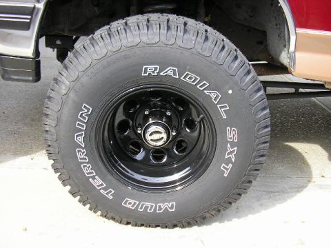 1994 Ford Bronco - A close-up view of a vehicle's wheel and tire, showing the tread pattern and sidewall markings.