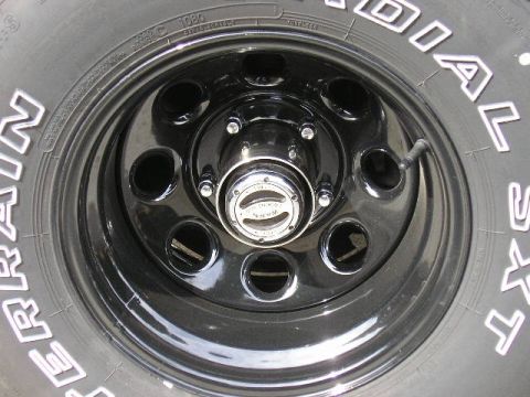 1994 Ford Bronco - Close-up of a black steel wheel with a chrome hubcap and visible tire tread.