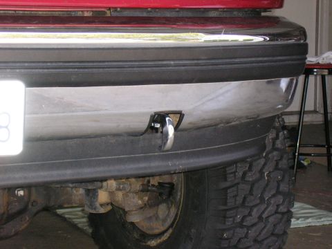 1994 Ford Bronco - A tow hook is installed on the front bumper of a vehicle, with a large tire in view.