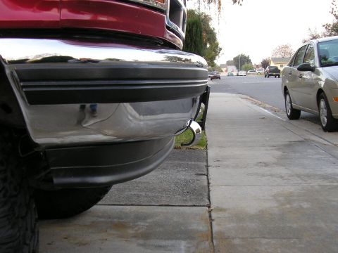 1994 Ford Bronco - Close-up of a red truck's front bumper, showing a chrome finish and an installed tow hook.