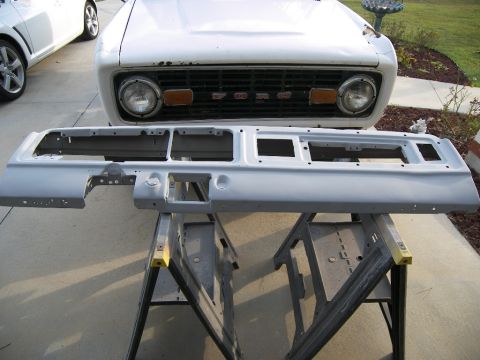 1978 Ford Bronco - A white 1978 Ford Bronco's front grille and headlights are visible behind a removed dashboard assembly resting on sawhorses.