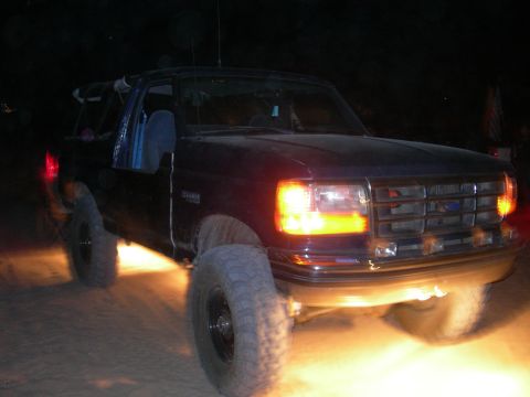 1994 Ford Bronco - This dark SUV, likely a 1992 model, is seen at night with its headlights on.