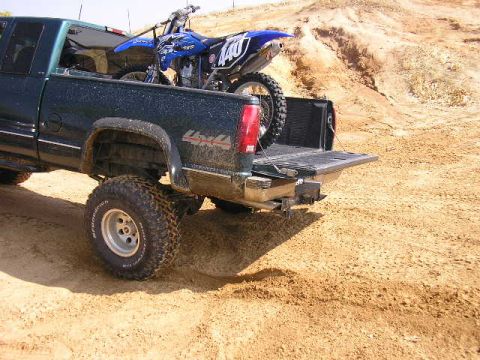 1994 Ford Bronco - A dirt bike is loaded into the bed of a pickup truck, ready for off-road adventures.