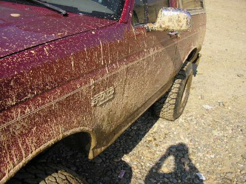 1994 Ford Bronco - This Ford Bronco is covered in mud after off-roading. The 'Bronco' badge is visible on the door.