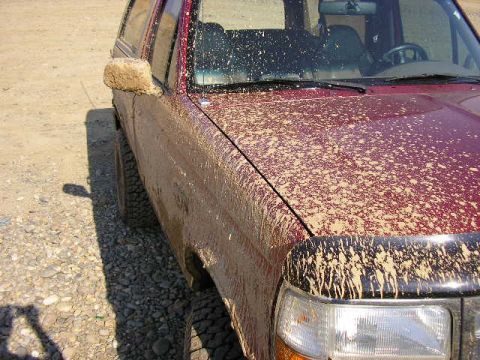 1994 Ford Bronco - This maroon SUV is heavily splattered with mud, obscuring its details.