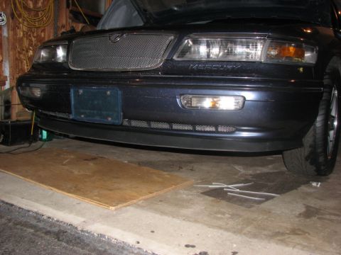 1985 Mercury Grand Marquis - Dark blue Mercury sedan's front end, showing the mesh grille and headlights. The word MERCURY is visible.