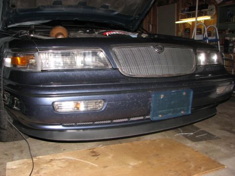1985 Mercury Grand Marquis - The front of a dark blue sedan is shown with its hood open, revealing the engine compartment.