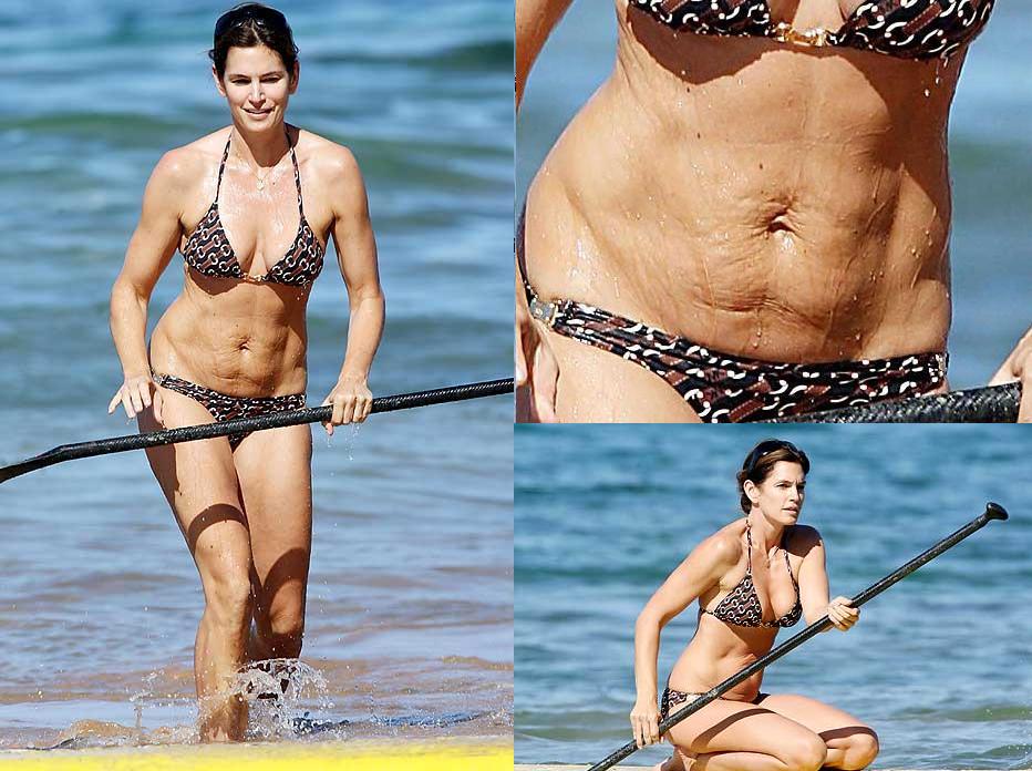 Woman in a patterned bikini on a paddleboard in the ocean, holding a paddle