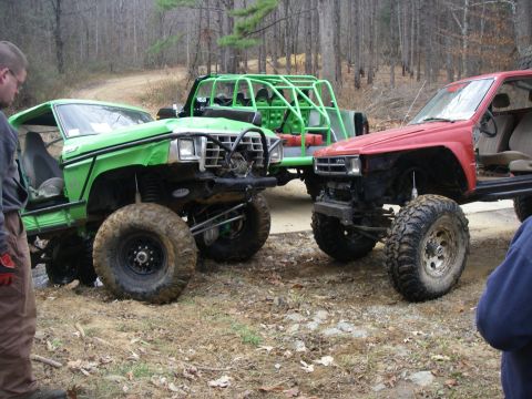 1978 Ford Bronco - Several custom off-road vehicles are gathered on a dirt trail surrounded by trees.