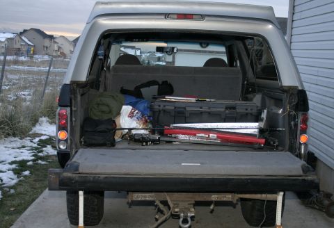 1994 Ford Bronco - The rear of a silver Ford Bronco is open, revealing camping gear and a toolbox. The vehicle appears to be from the early to mid-1990s.