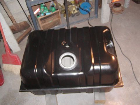 1991 Ford Bronco - A black fuel tank sits on a surface, with cleaning supplies and tools in the background.