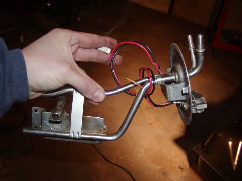1991 Ford Bronco - A person holds a fuel pump sending unit, likely for replacement or inspection.