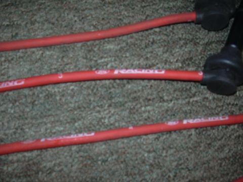 1997 Ford Crown Victoria - Red spark plug wires with white 'RACING' text are laid out on a carpeted surface.