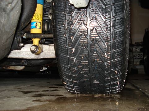 1998 Ford Taurus - A close-up view of a car's tire and suspension system, a yellow Bilstein shock absorber.