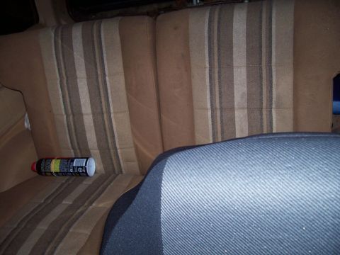 1984 Ford Bronco II - A can rests on the striped upholstery of a vehicle's rear seats.