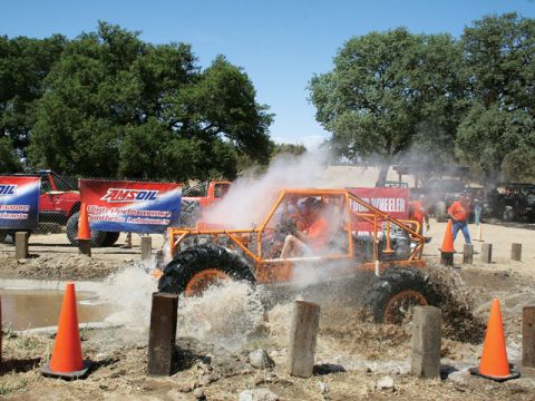1973 Ford Bronco - An off-road buggy navigates a muddy obstacle course, kicking up water and steam.