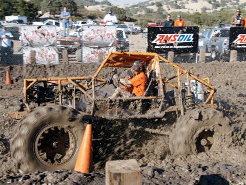 1973 Ford Bronco - A custom-built buggy navigates a challenging mud race course, kicking up significant spray.