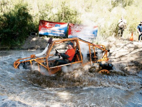 1973 Ford Bronco - An orange off-road buggy navigates a water obstacle, with AMSOIL banners visible behind it.