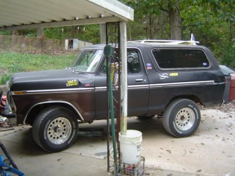 1979 Ford Bronco - This Ford Bronco has a two-tone paint job and aftermarket wheels, with a surfboard strapped to its roof.