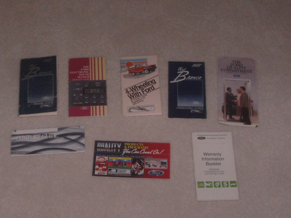 Several Ford Bronco manuals and brochures laid out, including an operating guide labeled 1988