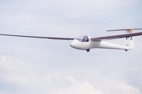 2003 Ford Crown Victoria - A white glider aircraft is captured in mid-flight against a cloudy sky.
