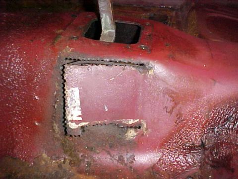 1967 Mercury Cougar - Close-up of a rusted car floor pan showing a cut-out section and a metal lever.