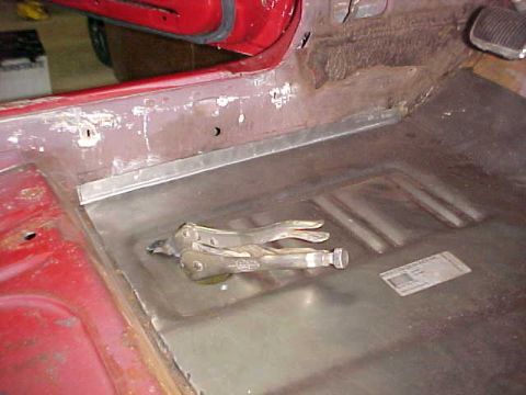 1967 Mercury Cougar - A clamp holds metal in place on a car's floor during repair work.