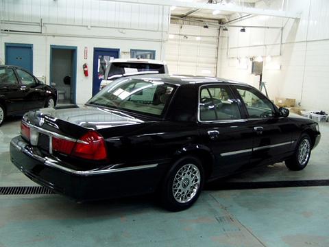 2000 Mercury Grand Marquis - A black 2000 Mercury Grand Marquis is parked inside a garage, with another vehicle partially visible on the left.