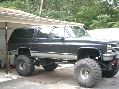 1991 Chevrolet Suburban - A heavily modified 1991 Chevrolet Suburban is shown with its lifted chassis and large tires.