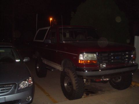 1992 Ford Bronco - 1992 Ford Bronco parked at night, showing its lifted suspension and large off-road tires.